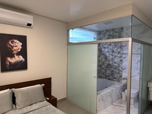 a bedroom with a glass shower and a tub at AR Pousada in Santa Bárbara