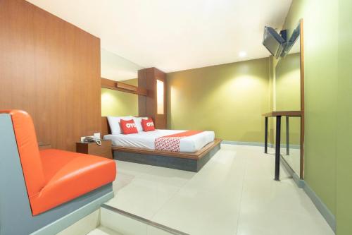 a bedroom with a bed and an orange chair at OYO 75382 Chonburi Hotel in Chon Buri