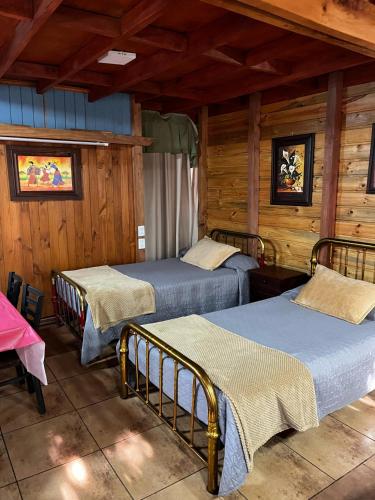 two beds in a room with wooden walls at Hostal Puerta del Sol Molina in Molina