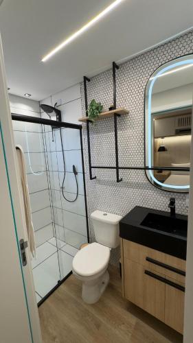 a bathroom with a toilet and a sink and a mirror at Loft Premium em Pomerode in Pomerode