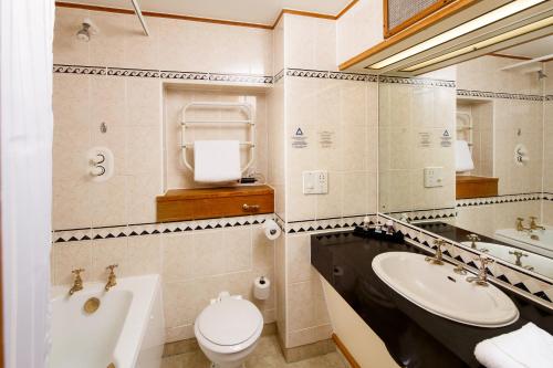 a bathroom with a sink and a toilet and a tub at Mercure York Fairfield Manor Hotel in York