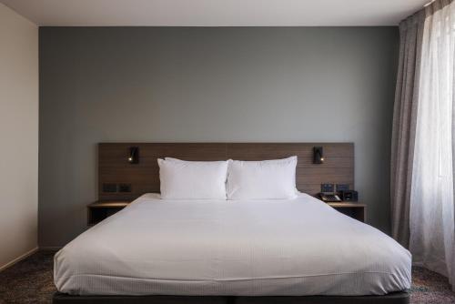 a bedroom with a large bed with white sheets and pillows at Heartland Hotel Auckland Airport in Auckland