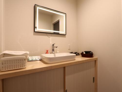 a bathroom with a sink and a mirror on the wall at ホテル森のしずく in Shimoda