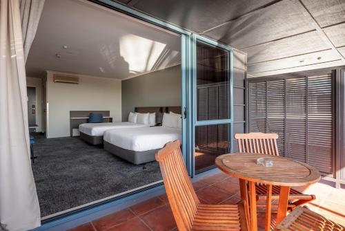 a hotel room with a bed and a table and chairs at Heartland Hotel Auckland Airport in Auckland