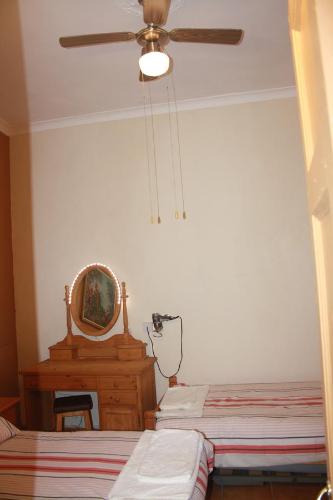 a bedroom with two beds and a mirror and a ceiling fan at Governor's Inn Apartments in Gibraltar