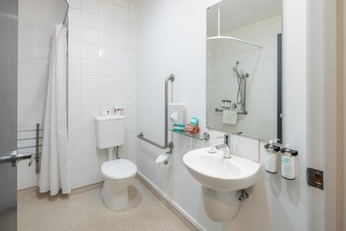 a white bathroom with a toilet and a sink at Heartland Hotel Auckland Airport in Auckland