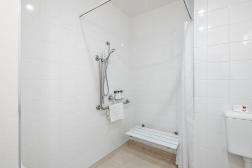 a white bathroom with a shower and a toilet at Heartland Hotel Auckland Airport in Auckland