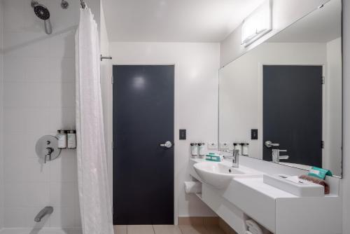 a white bathroom with two sinks and a shower at Heartland Hotel Auckland Airport in Auckland