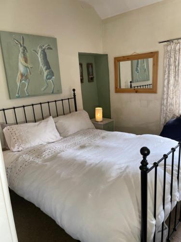a bedroom with a large bed with white sheets at Red Dragon Cottages nr Mt Snowdon in Beddgelert