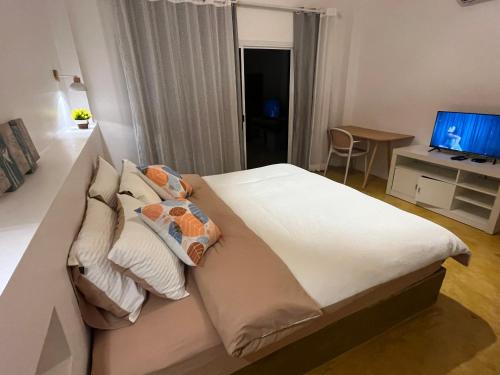 a bedroom with a large white bed and a television at The Summer Cottage in Khlaung Phai Bae
