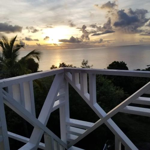 a sunset over the ocean with a white fence at Southern Sunset Villa in Choiseul