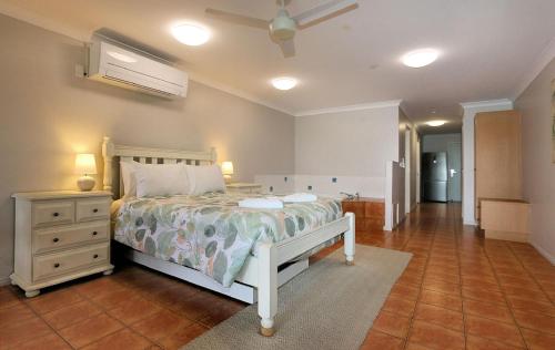 ein Schlafzimmer mit einem weißen Bett, einer Kommode und einem Ventilator in der Unterkunft Villa 7 1 Pebble Beach Drive Coral Cove in Elliott Heads