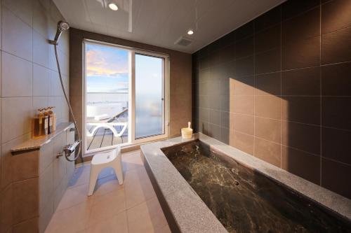 a bathroom with a bath tub with a window at クリスタルヴィラ白浜パークサイド in Shirahama