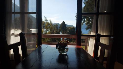 a wooden table with a vase on top of it with a window at CASA del LAGO Bariloche in San Carlos de Bariloche