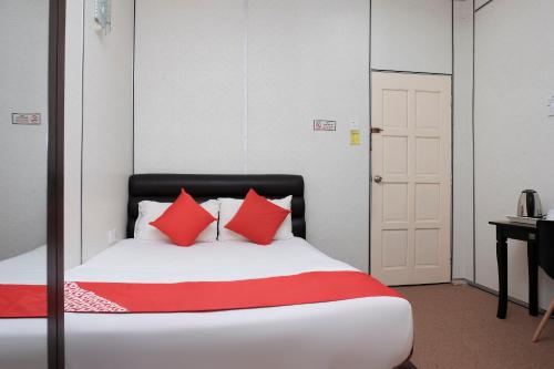 a bedroom with a bed with red pillows and a desk at OYO 90180 Gemilang Hotel Kerteh in Dungun