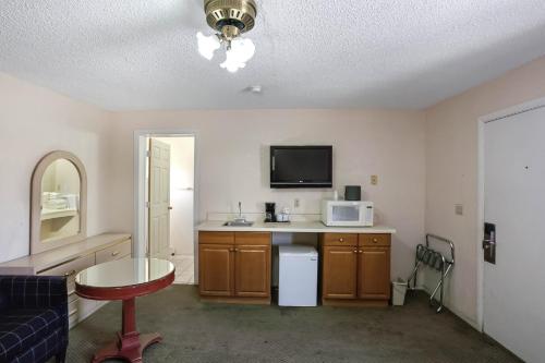 a room with a kitchen with a microwave and a table at OYO Hotel Yuma AZ - I-8 US-95 in Yuma
