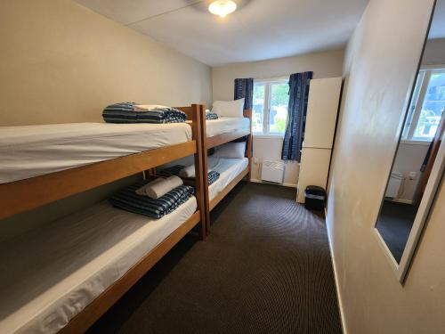 a dorm room with two bunk beds and a window at Pinewood Queenstown in Queenstown