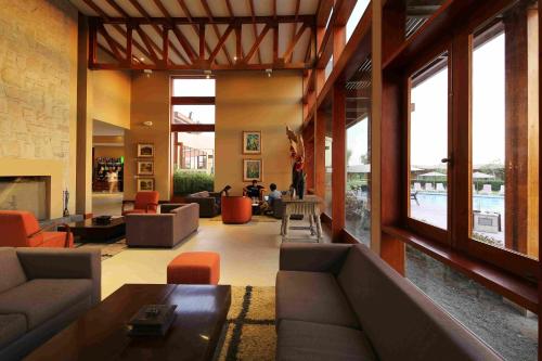 a living room with couches and tables and windows at Casa Andina Standard Chincha in Chincha Alta