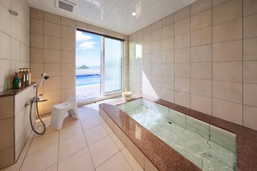 a bathroom with a tub and a window at クリスタルヴィラ白浜パークサイド in Shirahama