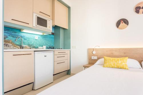 a kitchen with a sink, microwave, and refrigerator at Apartamentos Ferrer Tamarindos in Port d'Alcudia