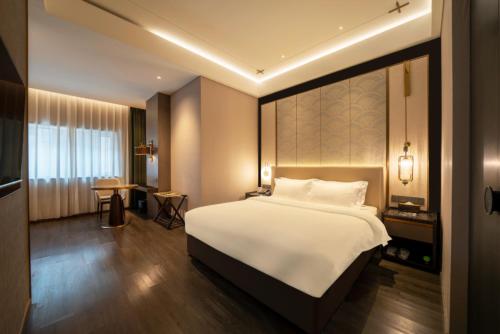 a bedroom with a large white bed and a table at THE YARD HOTEL BEIJING,BianyiFang - steps The Forbidden City - strolling through the imperial gardens is incredibly easy - The guest rooms blend modern comfort with Chinese charm - Peking duck - living in history Your Beijing adventure begins here in Beijing