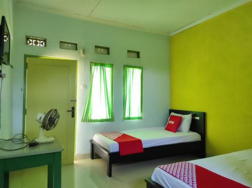 a bedroom with two beds with green walls and a fan at OYO 90333 Wisma Tenang Jaya Syariah in Majalengka