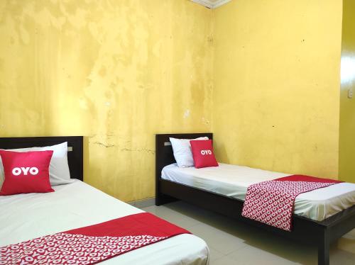 two beds in a room with red and white pillows at OYO 90333 Wisma Tenang Jaya Syariah in Majalengka