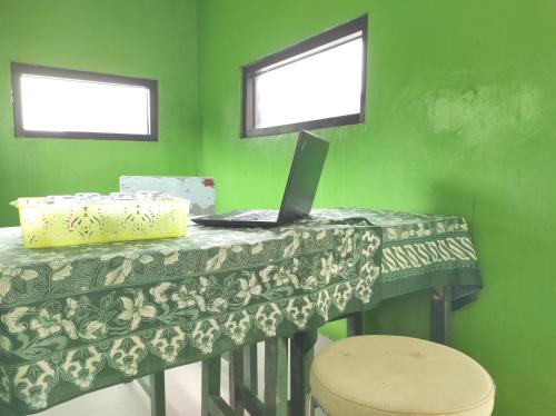 a green room with a table with a laptop on it at OYO 90333 Wisma Tenang Jaya Syariah in Majalengka