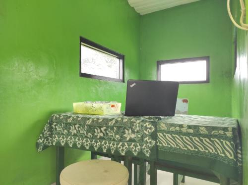 a green room with a table with a laptop on it at OYO 90333 Wisma Tenang Jaya Syariah in Majalengka