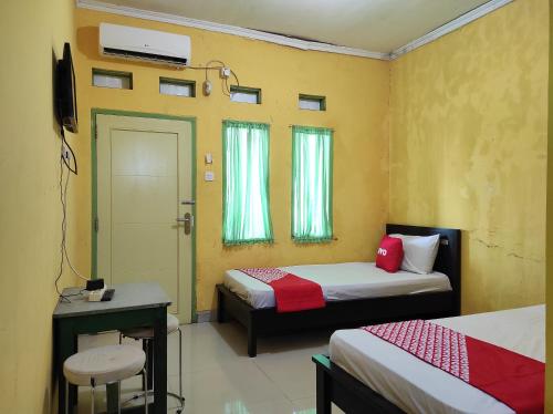 a room with two beds and a table and a window at OYO 90333 Wisma Tenang Jaya Syariah in Majalengka