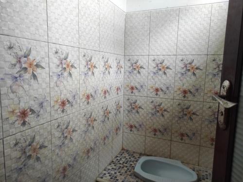 a bathroom with a toilet and flowers on the wall at OYO 90333 Wisma Tenang Jaya Syariah in Majalengka