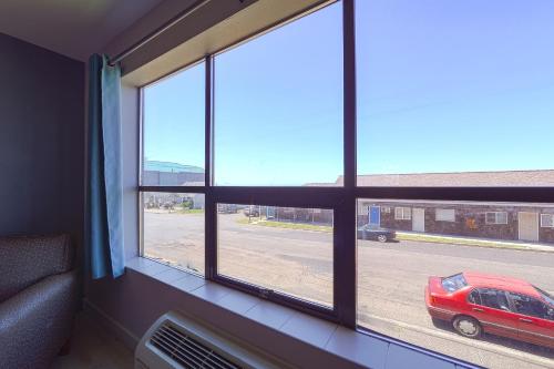 a room with a window with a red car parked on a street at OYO Waves Hotel Newport OR - NYE Beach in Newport