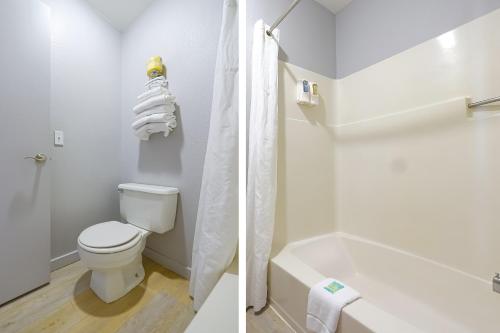 a white bathroom with a toilet and a bath tub at OYO Waves Hotel Newport OR - NYE Beach in Newport