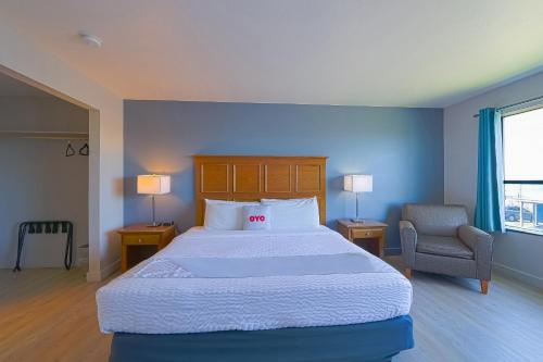 a bedroom with a large bed and a chair at OYO Waves Hotel Newport OR - NYE Beach in Newport