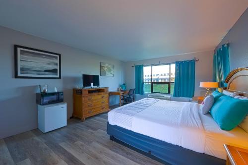 a bedroom with a bed and a desk with a television at OYO Waves Hotel Newport OR - NYE Beach in Newport