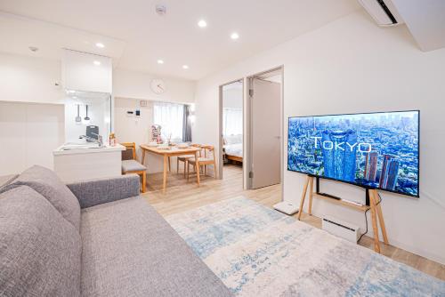 a living room with a couch and a tv on a wall at self-check in misimaya building in Tokyo