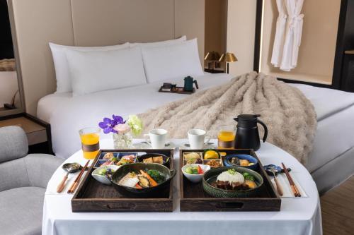 a tray of food on a table in front of a bed at Voyage Kaohsiung By Cosmos Oasis in Kaohsiung