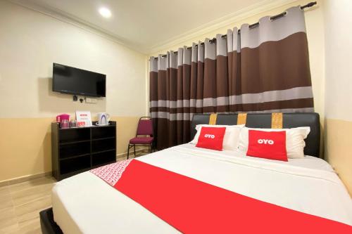 a bedroom with a bed with red pillows and a tv at Hotel O Bayu Sintok Motel in Changlun