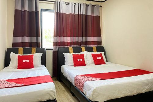 two beds in a room with red pillows at Hotel O Bayu Sintok Motel in Changlun