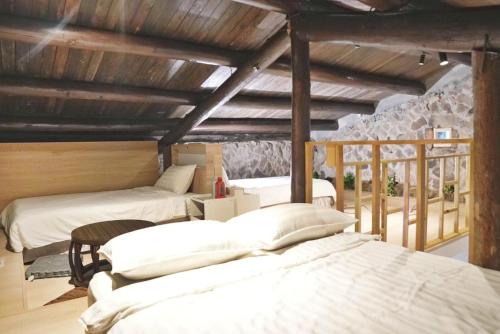a room with three beds and a stone wall at 九份輕旅民宿 in Jiufen