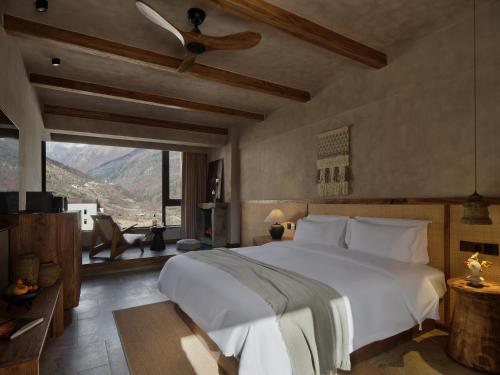a bedroom with a large white bed and a large window at Mount Sigunian Looking up at the snowy peak Vacilando Hotel in Mount Siguniang