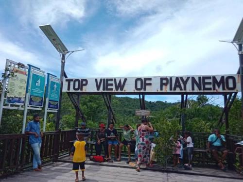 a group of people standing under a top view of playneemo sign at Mares Homestay-Raja Ampat in Fam