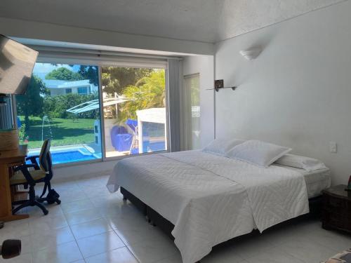 Un dormitorio con una cama y vistas a una piscina. en HERMOSA VILLA FAMILIAR CONDOMINIO CAMPESTRE EL PEÑON Piscina Privada Campo de Golf, en Girardot
