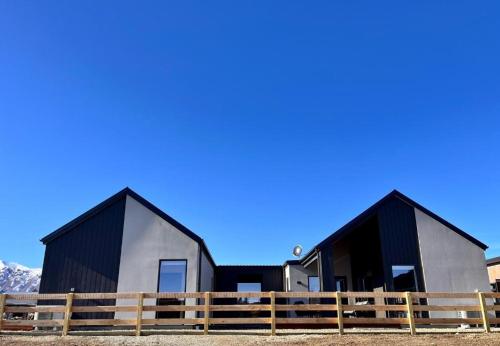 a house with black and gray roofs and a fence at The Peaks - Lake Tekapo in Lake Tekapo