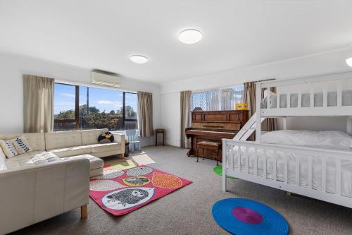 Un dormitorio con una litera y una sala de estar con un piano. en Sandbanks - Papamoa Beachfront Holiday Home, en Papamoa