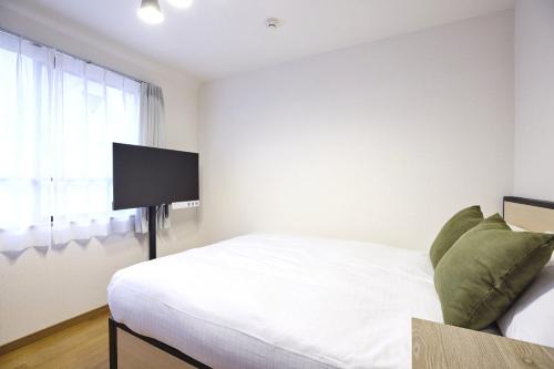 a bedroom with a bed and a flat screen tv at Station Fujimigaoka in Kugayama