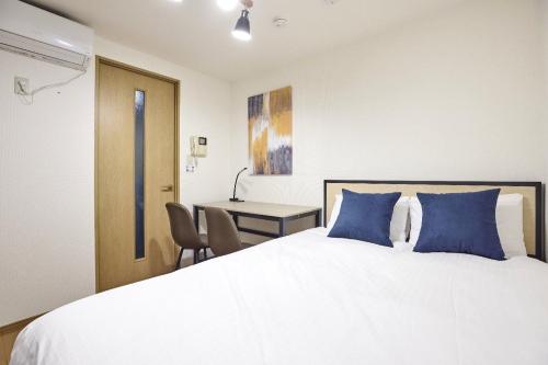 a bedroom with a bed with blue pillows and a desk at Station Fujimigaoka in Kugayama