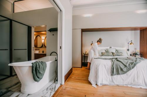 a woman in a bedroom with a bed and a bathtub at Littlebourne Guest House in Bathurst