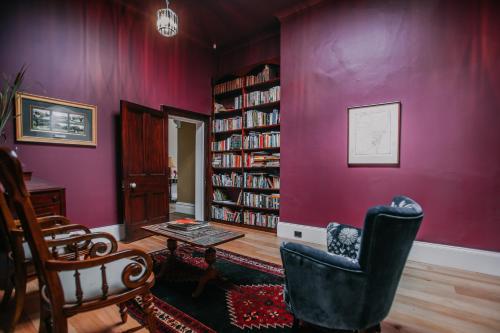 a living room with purple walls and a book shelf at Littlebourne Guest House in Bathurst