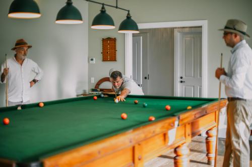 a man playing pool with three men standing around at Littlebourne Guest House in Bathurst